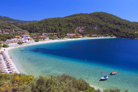 Πανοραμική φωτογραφία του οικισμού και της παραλίας Πάνορμος με τα γαλαζοπράσινα νερά της θάλασσας σκοπελοσ παραλιεσ