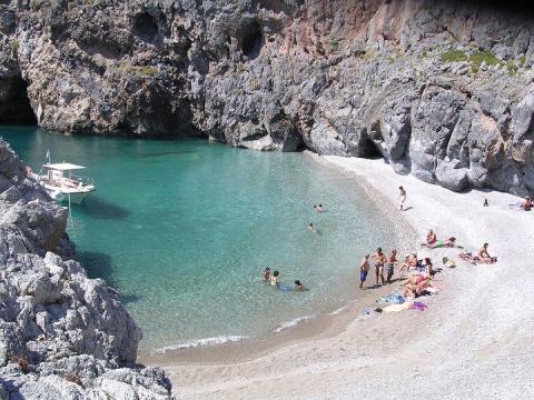 κυθηρα παραλιεσ Άνθρωποι κάθονται στην ακρογιαλιά και άλλοι αποάμβάνουν το μπάνιο τους στα κρυστάλινα νερά στην Παραλία Καλάμι