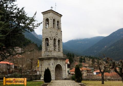 Το καμπαναριό της εκκλησίας στο μικρο χωριο και στο φόντο τα σπίτια του οικισμού