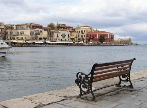 Ένα παγκάκι στη παραλία και στο φόντο χανια παλια πολη