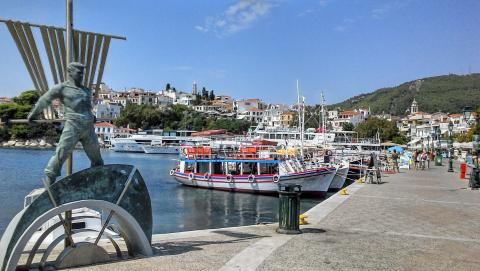 Ο παραλιακός περίπατος στο λιμάνι της Σκιάθου με το άγαλμα του ναύτη και αραγμένες βαρκούλεςπαραλιεσ σκιαθου