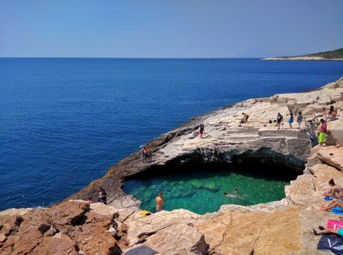 κρυστάλλινα νέρα της λιμνοθάλασσας γκιόλα θασοσ ανθρωποι στα βράχια και στο φόντο η θάλασσα