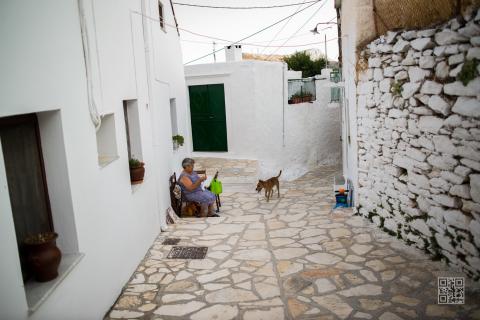 Πλακόστρωτο καλντερίμι στην απειρανθοσ και μια κυρία που πλέκει