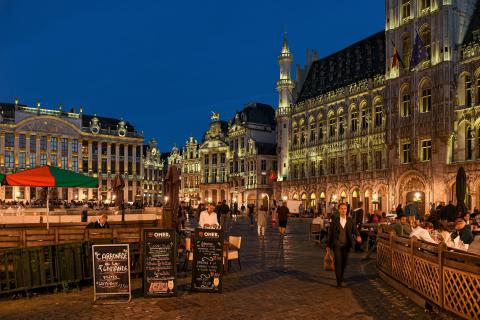 Άνθρωποι δειπνούν σε εστιατόριο της Γκραν Πλας Βρυξελλών με τα γύρω κτίρια φωτισμένα